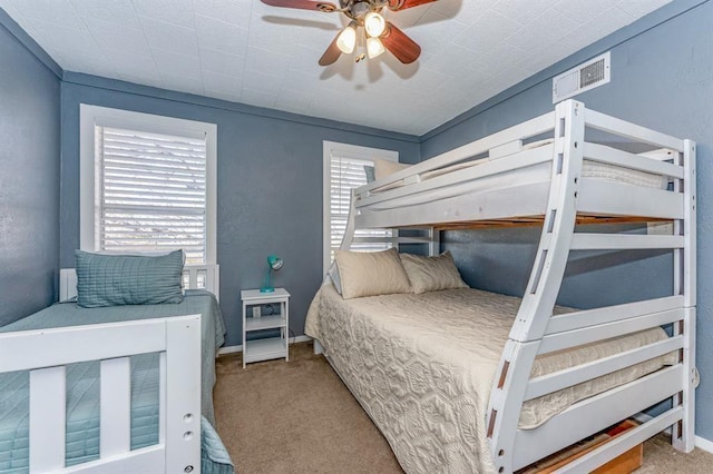 bedroom with multiple windows, ceiling fan, and light colored carpet