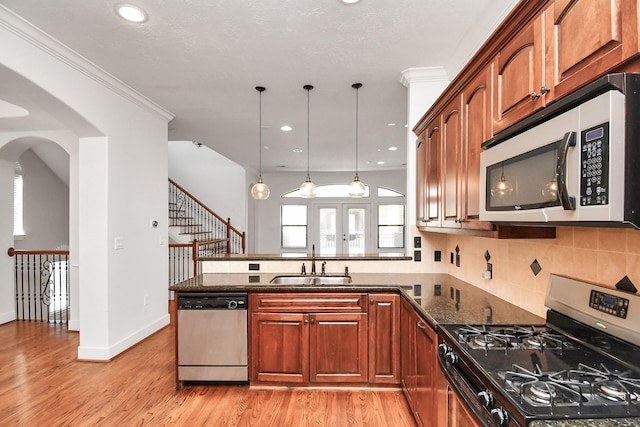 kitchen with pendant lighting, sink, light hardwood / wood-style flooring, dark stone countertops, and appliances with stainless steel finishes