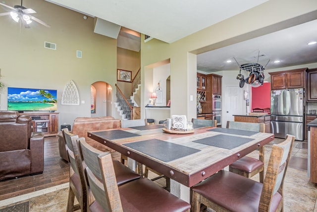 dining room featuring ceiling fan, a towering ceiling, and light hardwood / wood-style flooring