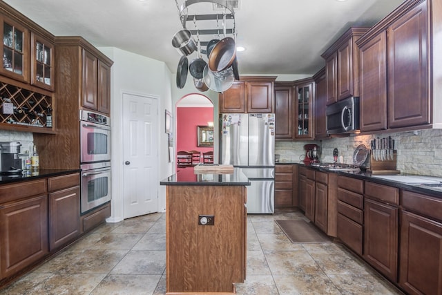 kitchen featuring tasteful backsplash, a center island, stainless steel appliances, and dark brown cabinets