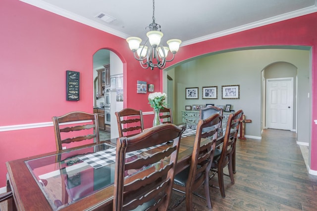 dining space featuring dark hardwood / wood-style floors, an inviting chandelier, and crown molding