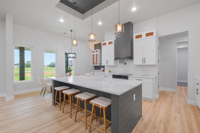 kitchen featuring white cabinets, a large island, light stone counters, and hanging light fixtures