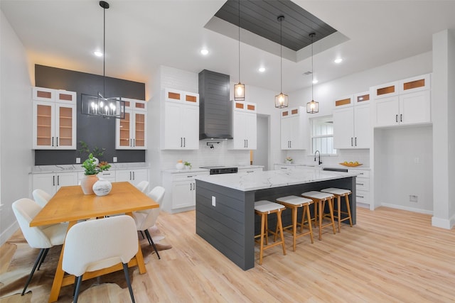 kitchen with light stone countertops, decorative backsplash, a kitchen island, white cabinetry, and hanging light fixtures