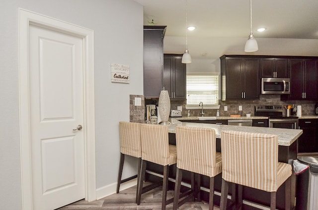 kitchen with a kitchen bar, stainless steel appliances, kitchen peninsula, and hanging light fixtures