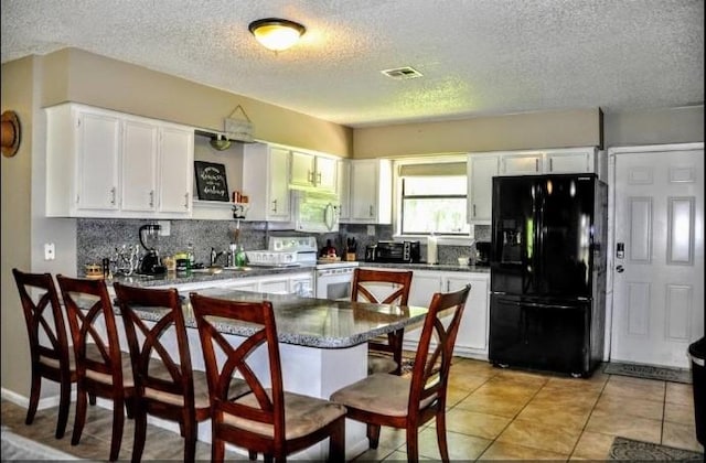 kitchen with kitchen peninsula, tasteful backsplash, a textured ceiling, white appliances, and white cabinets