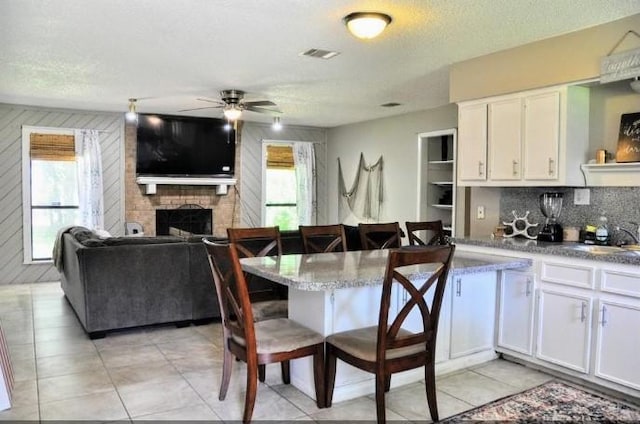 kitchen featuring a kitchen breakfast bar, white cabinetry, and a healthy amount of sunlight