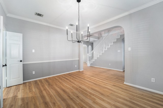 unfurnished dining area featuring hardwood / wood-style floors, ornamental molding, and an inviting chandelier