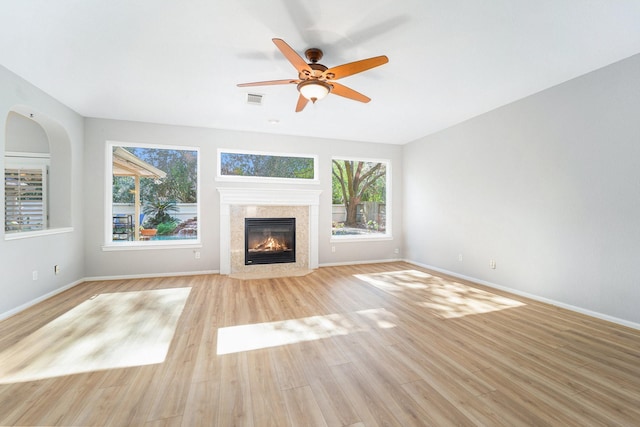 unfurnished living room with a high end fireplace, light hardwood / wood-style flooring, and ceiling fan