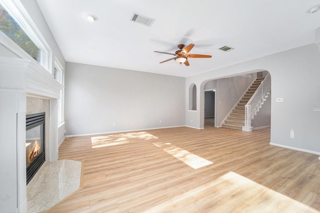 unfurnished living room featuring ceiling fan, a fireplace, and light wood-type flooring