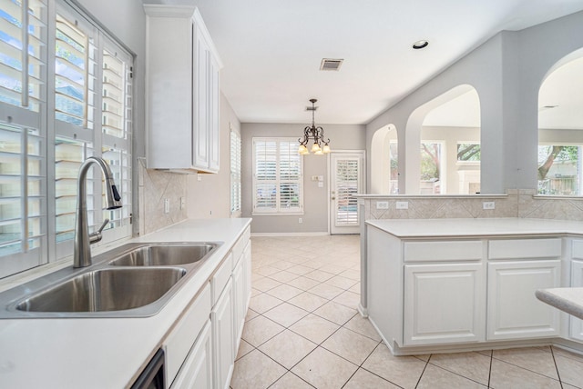 kitchen featuring light tile patterned flooring, white cabinetry, sink, and an inviting chandelier