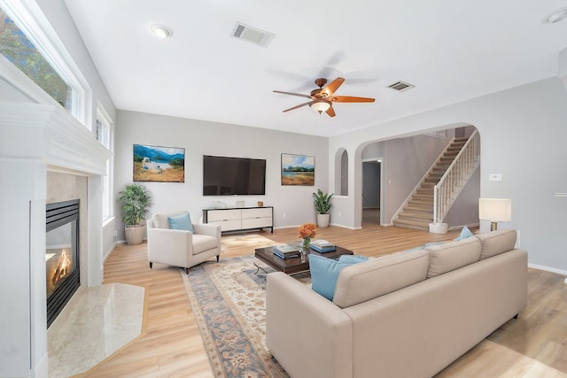 living room featuring ceiling fan, a fireplace, and light hardwood / wood-style flooring