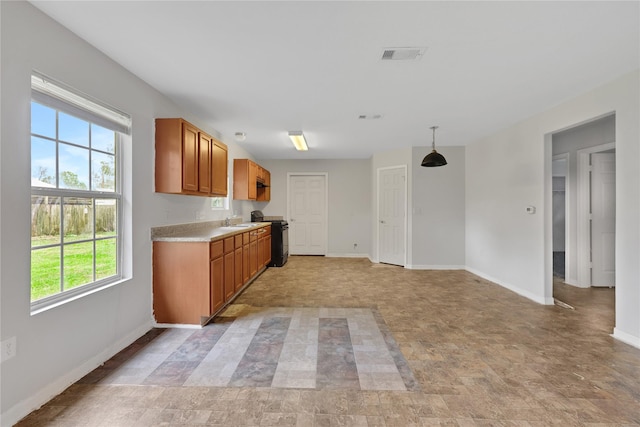 kitchen featuring pendant lighting, plenty of natural light, sink, and black range