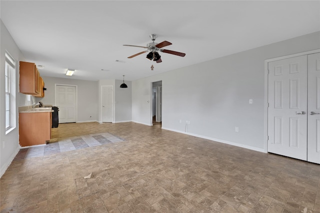 unfurnished living room with ceiling fan and sink