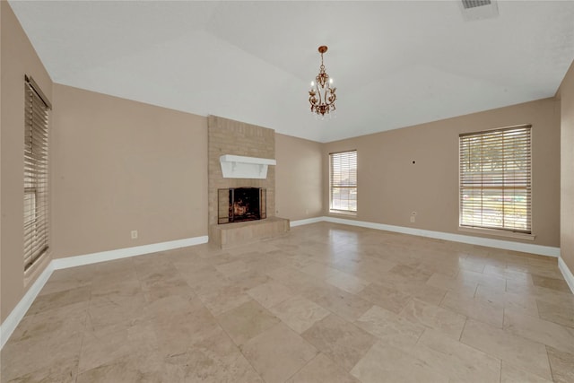 unfurnished living room with a large fireplace, plenty of natural light, lofted ceiling, and a notable chandelier