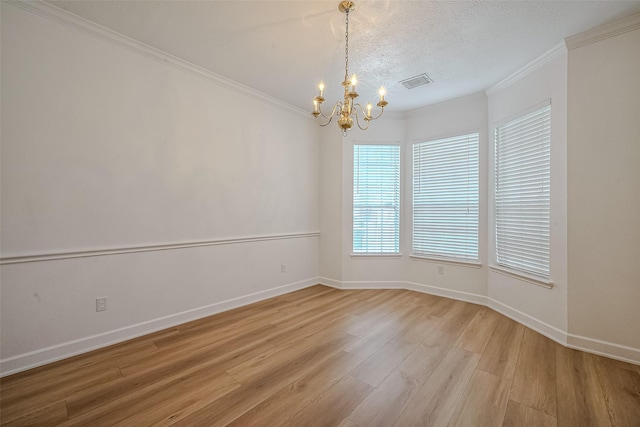 spare room with ornamental molding, light hardwood / wood-style floors, a textured ceiling, and an inviting chandelier