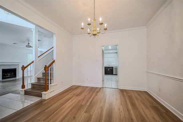 interior space with ceiling fan with notable chandelier, hardwood / wood-style flooring, plenty of natural light, and ornamental molding