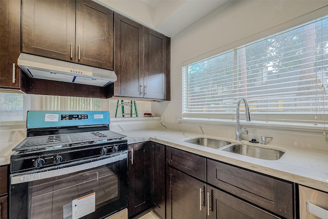 kitchen with dark brown cabinets, light stone counters, sink, and black gas range oven