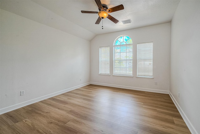 empty room with a textured ceiling, light hardwood / wood-style floors, ceiling fan, and lofted ceiling