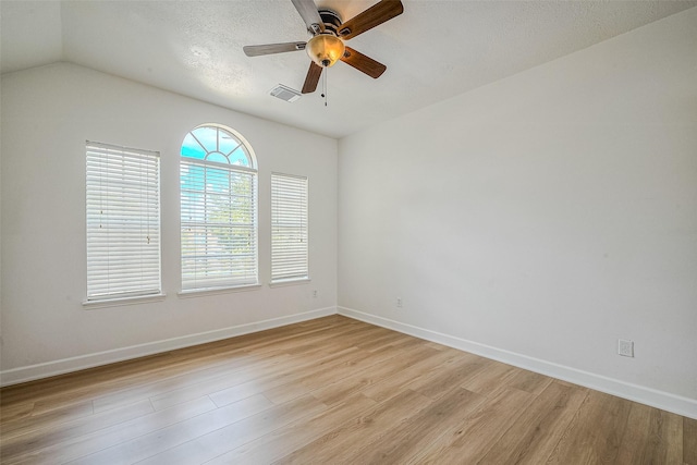 empty room featuring a textured ceiling, light wood-type flooring, ceiling fan, and lofted ceiling