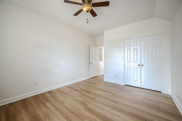 unfurnished bedroom featuring ceiling fan, light hardwood / wood-style floors, a closet, and vaulted ceiling