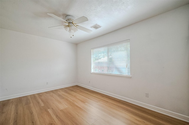 empty room with ceiling fan, light hardwood / wood-style flooring, and a textured ceiling