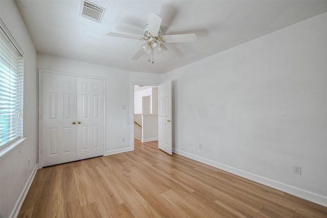 unfurnished bedroom featuring ceiling fan, a closet, a textured ceiling, and light hardwood / wood-style flooring