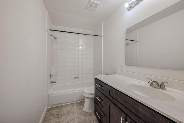 full bathroom featuring vanity, a textured ceiling, tiled shower / bath combo, tile patterned flooring, and toilet