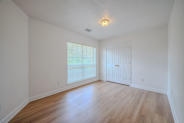 unfurnished bedroom featuring a textured ceiling, light hardwood / wood-style flooring, and a closet