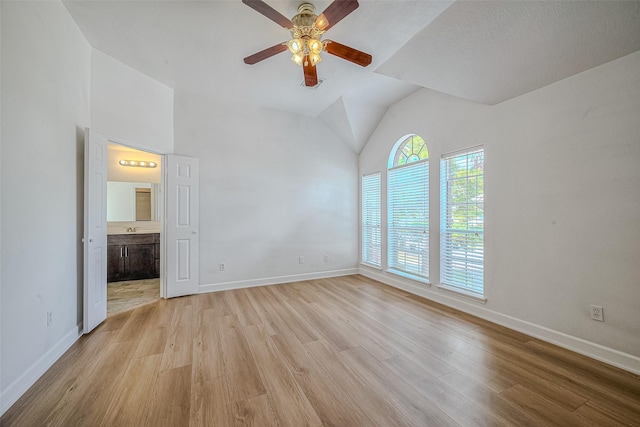 unfurnished bedroom featuring ceiling fan, vaulted ceiling, ensuite bath, and light hardwood / wood-style flooring