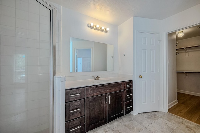 bathroom with vanity, wood-type flooring, a textured ceiling, and walk in shower