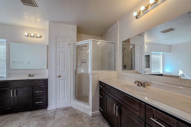 bathroom with vanity, a textured ceiling, tile patterned floors, and a shower with door