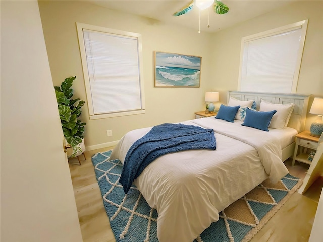 bedroom featuring multiple windows, light hardwood / wood-style floors, and ceiling fan