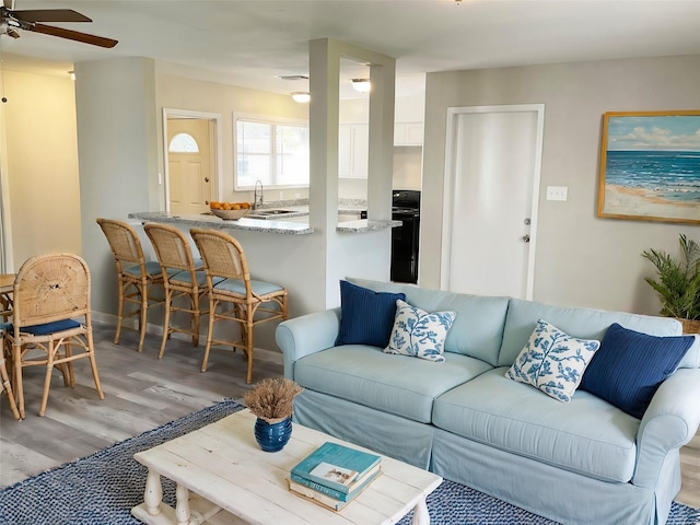 living room with ceiling fan, light wood-type flooring, and sink