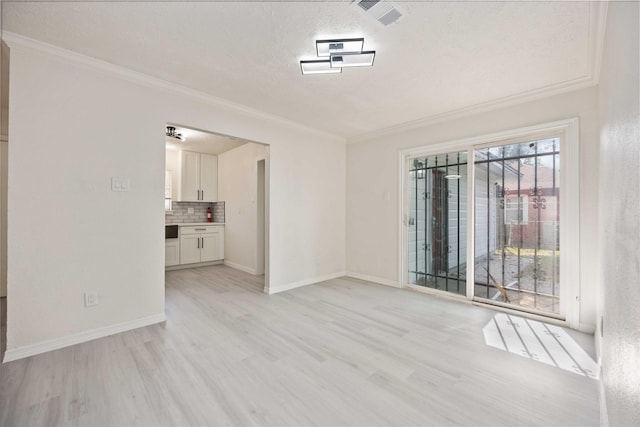 empty room featuring a textured ceiling, light wood-type flooring, and crown molding