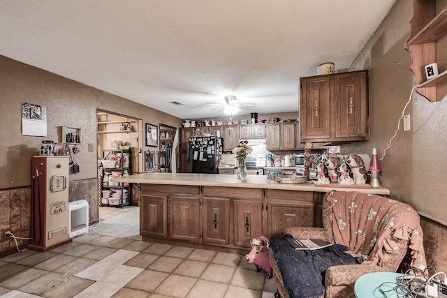 kitchen featuring ceiling fan, black refrigerator, and kitchen peninsula