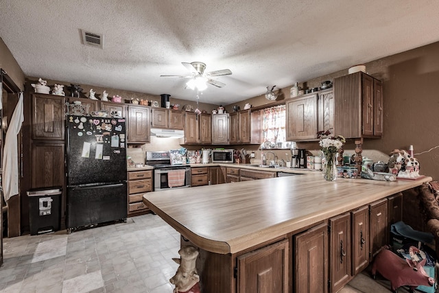 kitchen with sink, ceiling fan, a textured ceiling, appliances with stainless steel finishes, and kitchen peninsula