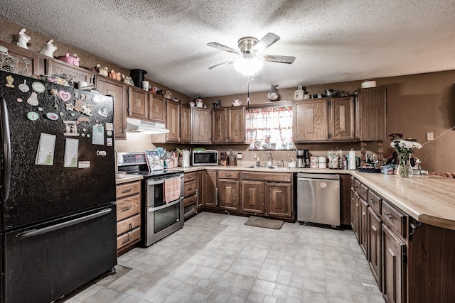 kitchen with dark brown cabinets, a textured ceiling, stainless steel appliances, and sink