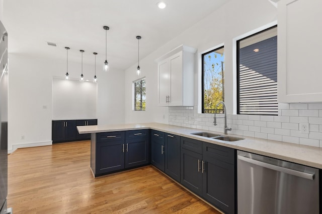 kitchen featuring pendant lighting, dishwasher, sink, kitchen peninsula, and white cabinetry