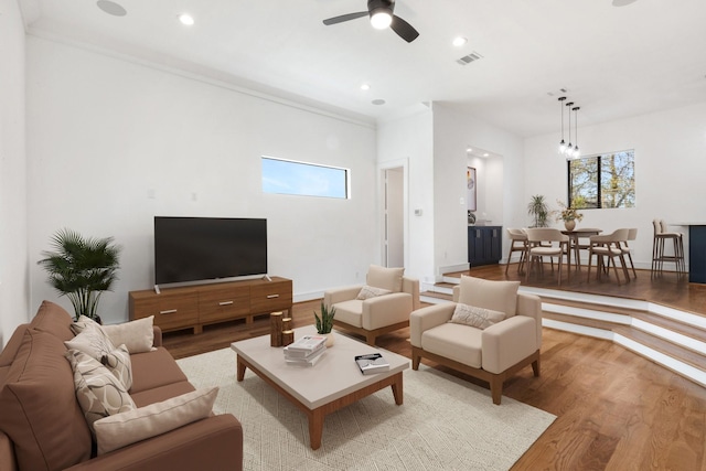 living room with ceiling fan, light hardwood / wood-style flooring, and crown molding