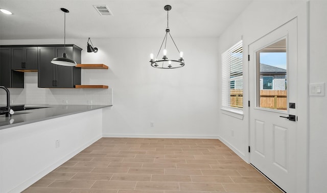 kitchen featuring decorative backsplash, light wood-type flooring, sink, decorative light fixtures, and a chandelier