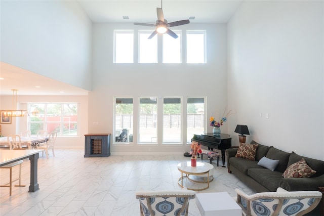 living room featuring a high ceiling and ceiling fan with notable chandelier