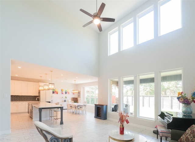 living room featuring ceiling fan with notable chandelier and a towering ceiling