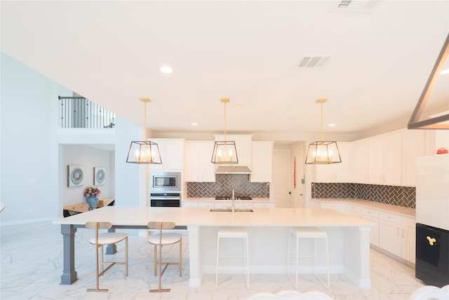 kitchen featuring pendant lighting, sink, white cabinetry, and a kitchen island with sink