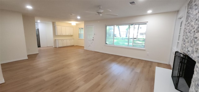 unfurnished living room with ceiling fan, a fireplace, and light wood-type flooring