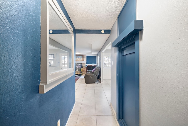 hall with a wealth of natural light, tile patterned flooring, and a textured ceiling