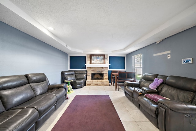 tiled living room with a fireplace, a textured ceiling, and a raised ceiling