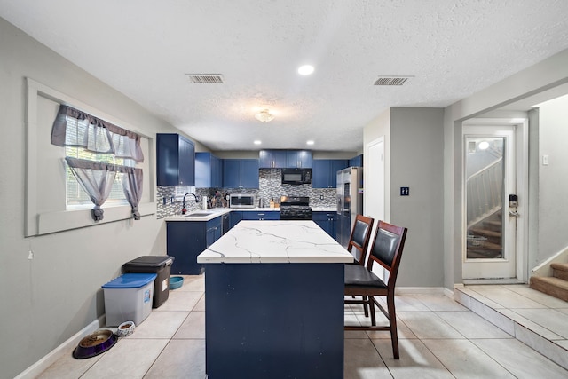 kitchen with a textured ceiling, blue cabinets, sink, black appliances, and a center island