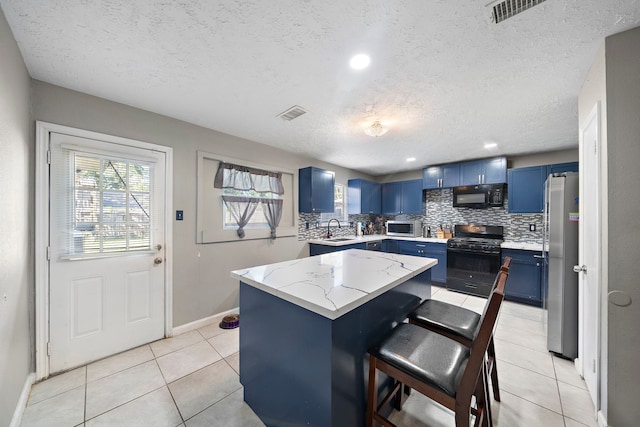 kitchen featuring black appliances, a center island, blue cabinetry, and a textured ceiling