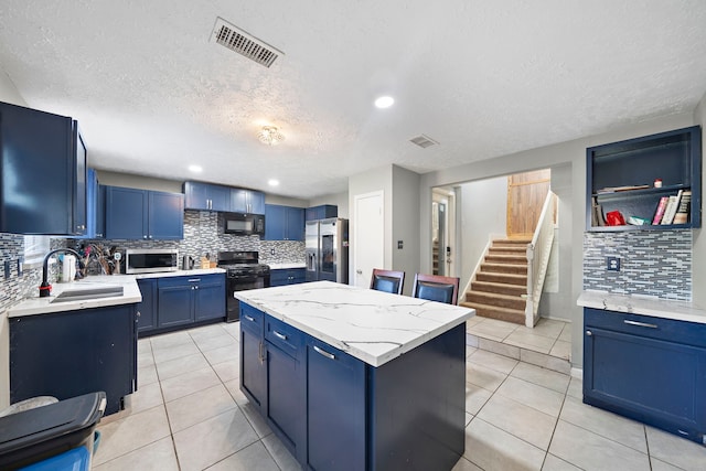 kitchen featuring tasteful backsplash, a textured ceiling, black appliances, blue cabinetry, and a kitchen island