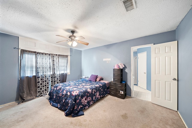 bedroom with ceiling fan, light colored carpet, and a textured ceiling